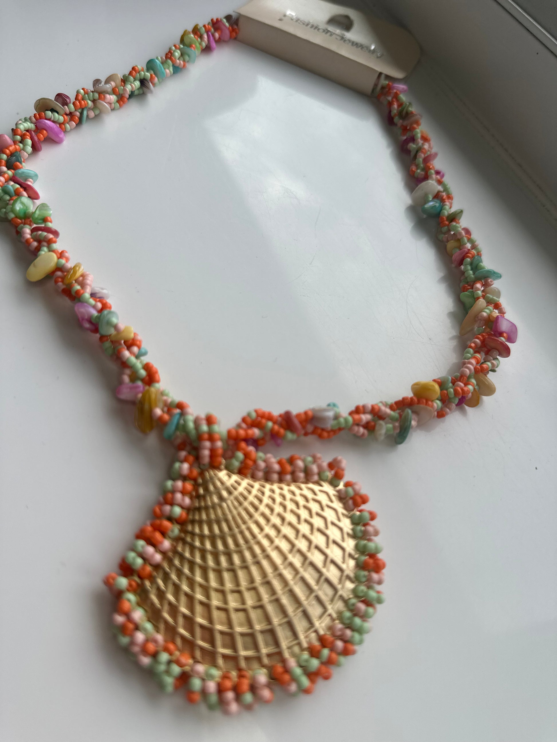 Colorful beaded necklace with a large gold shell pendant.