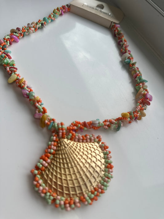 Colorful beaded necklace with a large gold shell pendant.